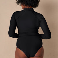 Woman wearing black Aire Turtle Neck a high neck, minimalist long sleeve women’s rashguard made from sustainable fabric, designed for sun protection and surf performance.