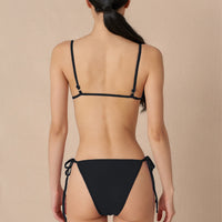 Woman wearing a black triangle bikini top with adjustable straps and removable cups, paired with matching bottoms made with sustainable swimwear fabrics.