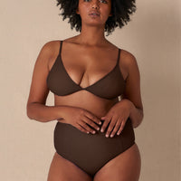 Woman wearing a brown minimalist triangle bikini top with adjustable straps and removable cups, paired with matching bottoms made with sustainable swimwear fabrics.