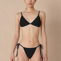 Woman wearing a black triangle bikini top with adjustable straps and removable cups, paired with matching bottoms made with sustainable swimwear fabrics.