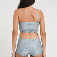 woman wearing a matching set of sea glass blue sustainable swimwear, consisting of a strapless top and low rise mini boy leg swim shorts.