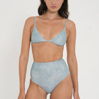 woman wearing fixed triangle bikini top in sea glass print, designed for both style and comfort. Crafted from 78% recycled nylon and 22% Lycra, offering a supportive and quick-drying fabric. Worn with matching high waisted sustainable swimwear bottoms.