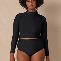 Woman wearing black Aire Turtle Neck a high neck, minimalist long sleeve women’s rashguard made from sustainable fabric, designed for sun protection and surf performance. 